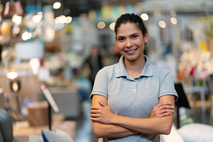 Confident female manager of a furniture store looking at camera smiling with arms crossed